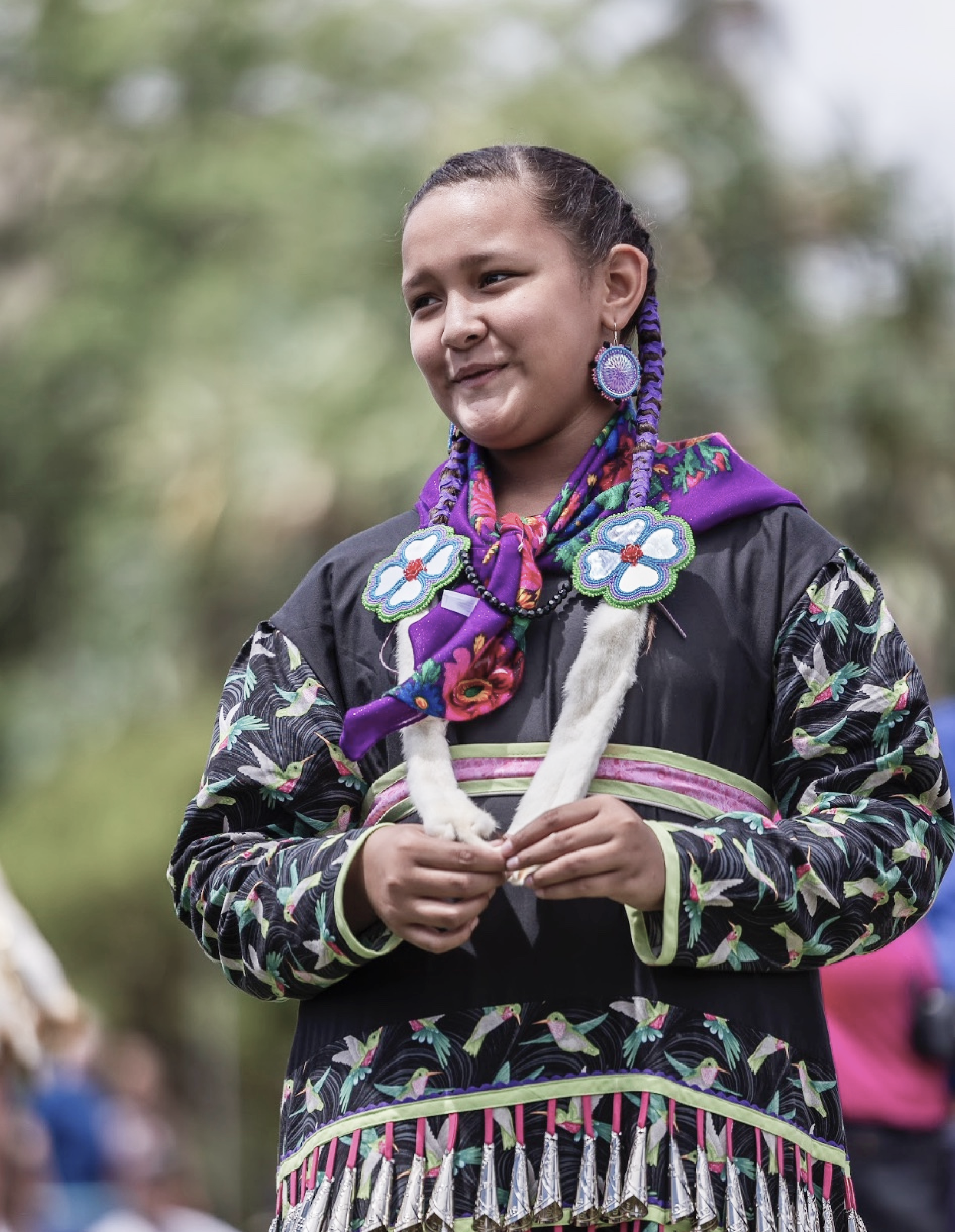 Moon Mare dressed in her traditional Native regalia (clothing and beadwork), smiling.